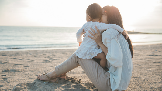 mom and baby sitting on beach