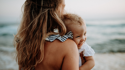 mom holding baby at the beach on holiday