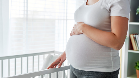 mom holding bump and standing in nursery